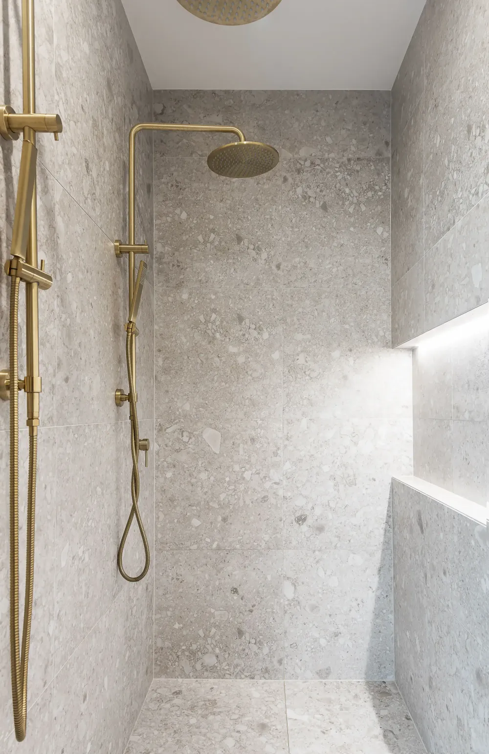 Shower with brass fixtures and stone tiling
